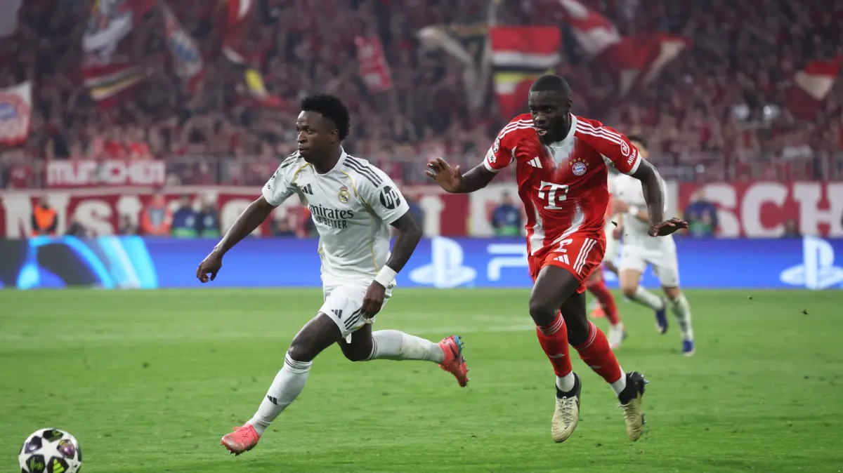 Real Madrid's Brazilian forward #07 Vinicius Junior (L) and Bayern Munich's French defender #02 Dayot Upamecano vie for the ball during the UEFA Champions League quarter-final second leg football match between FC Bayern Munich and Real Madrid in Munich, southern Germany, on April 15, 2026. (Photo by Karl-Josef HILDENBRAND / AFP)