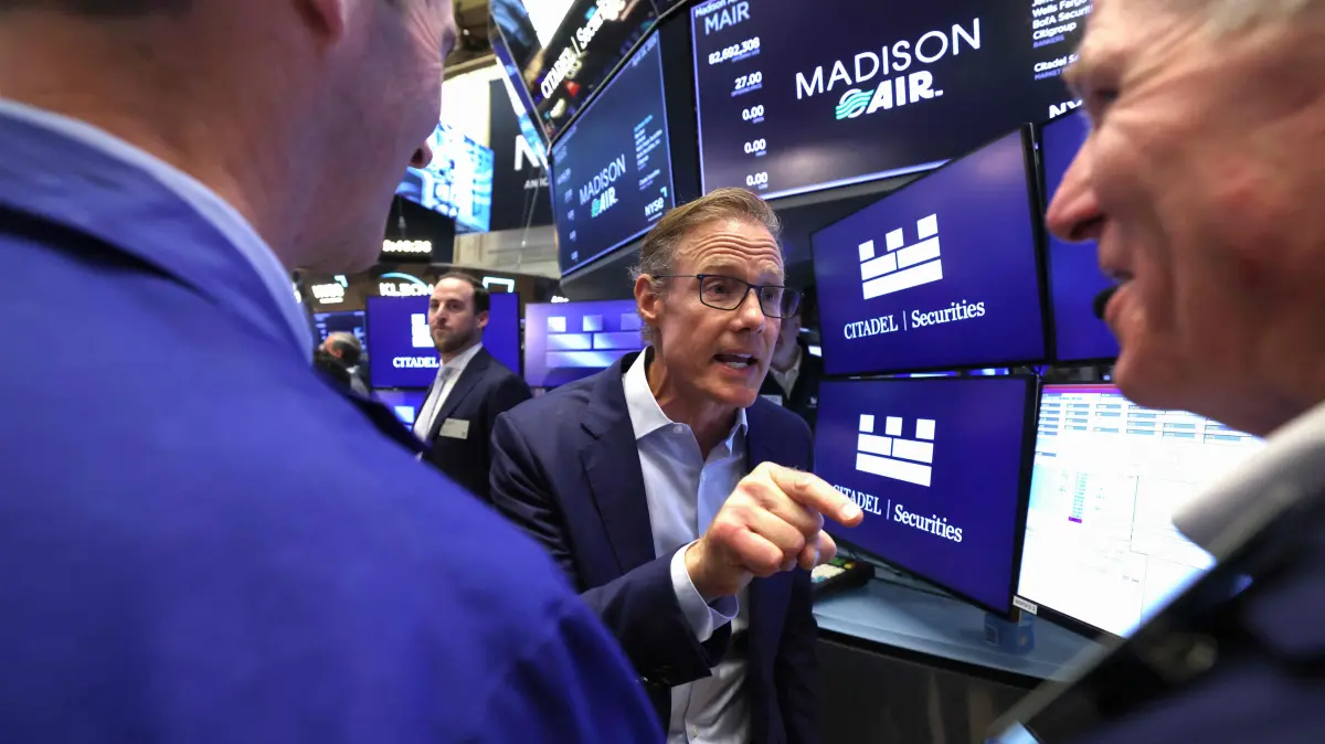 Madison Industries CEO Larry Gies (C) speaks with traders on the floor of the New York Stock Exchange (NYSE) after Gies rang the opening bell in New York on April 16, 2026. Wall Street stocks were little changed early Thursday, lingering near records amid hopes for a resolution of the US-Iran war as markets continue to shrug off economic effects. Both the S&P 500 and Nasdaq finished at records Wednesday as analysts pointed to an expected surge in equities if a peace deal is reached and to US bank earnings that showed American consumers remain healthy. (Photo by TIMOTHY A. CLARY / AFP)