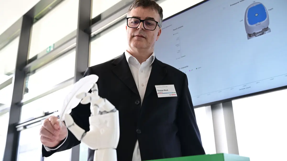 Bosch Jahrespressekonferenz: 16.04.2026, Baden-Württemberg, Renningen: Thomas Block, Globaler Produktmanager und Teamleiter für Magnet- und Umweltsensoren bei Bosch, steht vor einer Roboterhand mit einer Feder, mit der er die Sensoren ansteuert. Auf der Bilanzpressekonferenz werden die Geschäftszahlen bekannt gegeben. Foto: Bernd Weißbrod/dpa +++ dpa-Bildfunk +++