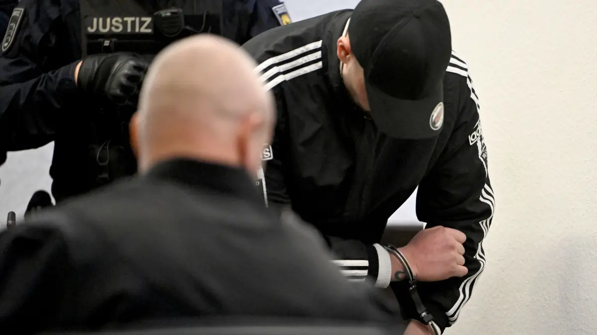 Urteil im Prozess nach tödlichem Autorennen: ARCHIV - 07.04.2026, Baden-Württemberg, Stuttgart: Einer der Angeklagten kommt im Landgericht in Handschellen zum Prozess wegen Mordes an zwei jungen Frauen nach einem Autorennen. Die zu der Tatzeit 32 Jahre, 34 Jahre und 25 Jahre alten Angeklagten sollen sich vor einem Jahr in Ludwigsburg zu einem illegalen «Beschleunigungsrennen» verabredet haben. (zu dpa: «Verurteilte Ludwigsburger Raser gehen gegen Haftstrafen vor») Foto: Marijan Murat/dpa +++ dpa-Bildfunk +++