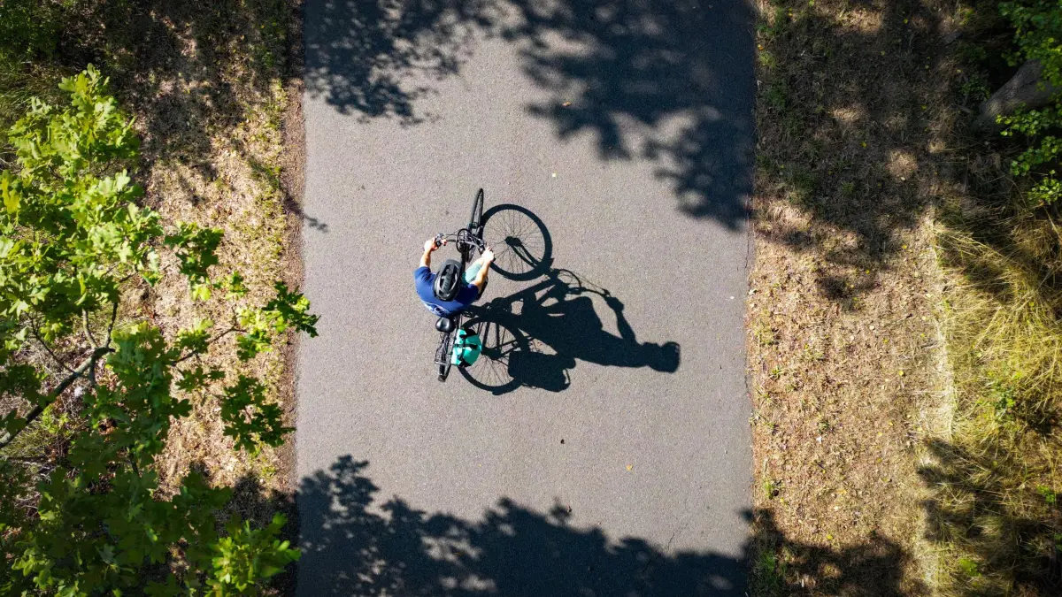 Radfahren in Brandenburg: PRODUKTION - 11.07.2025, Brandenburg, Großräschen: Tobias Nowakowski, wissenschaftlicher Mitarbeiter am Lehrstuhl für Umweltökonomie an der Brandenburgischen Technischen Universität Cottbus-Senftenberg (BTU), ist mit seinem Fahrrad auf dem Radweg «Kühle Spur» unterwegs. (Luftaufnahme mit einer Drohne) (zu dpa: «Saison der Radtouren beginnt in Brandenburg») Foto: Patrick Pleul/dpa +++ dpa-Bildfunk +++