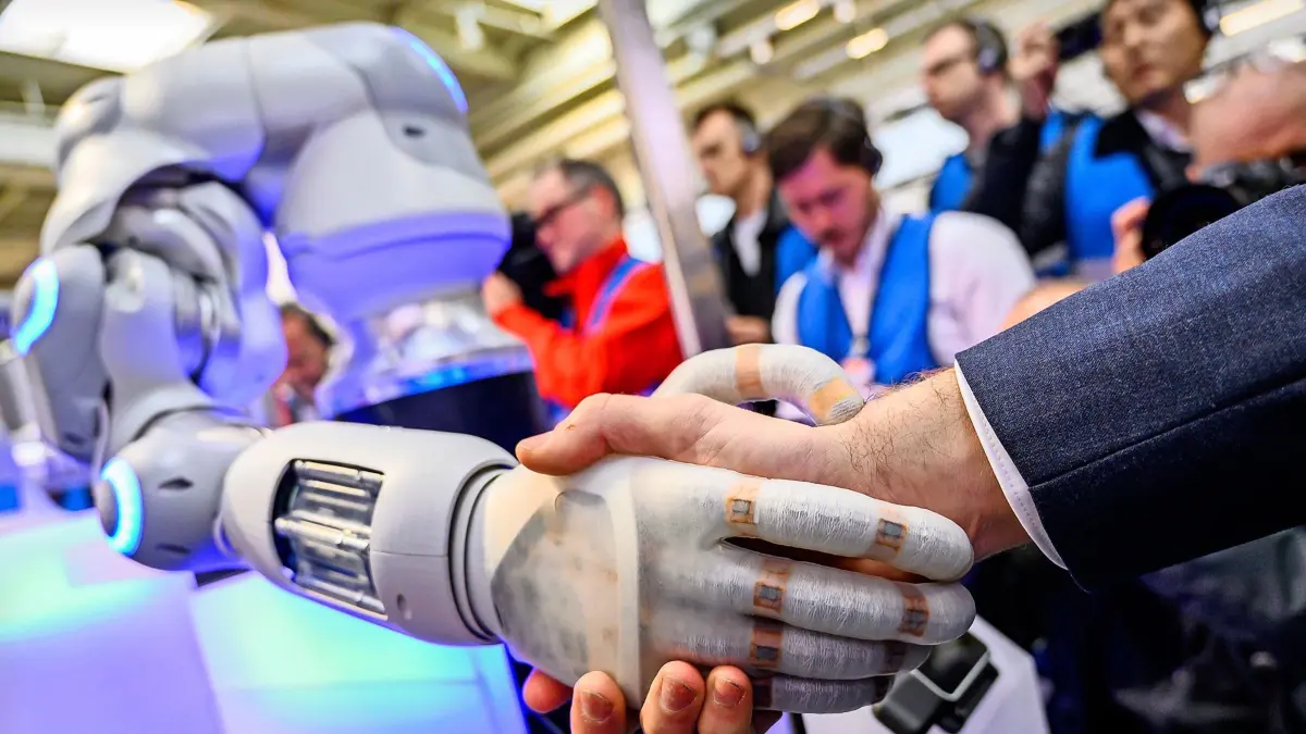 31.03.2019, Niedersachsen, Hannover: An einem Stand der Unternehmensgruppe für Steuerungs- und Automatisierungstechnik Festo gibt ein Roboter einem Mann die Hand. Vom 1. bis zum 5. April dreht sich auf der Hannover Messe alles um Vernetzung, lernende Maschinen und das Internet der Dinge. Foto: Christophe Gateau/dpa +++ dpa-Bildfunk +++