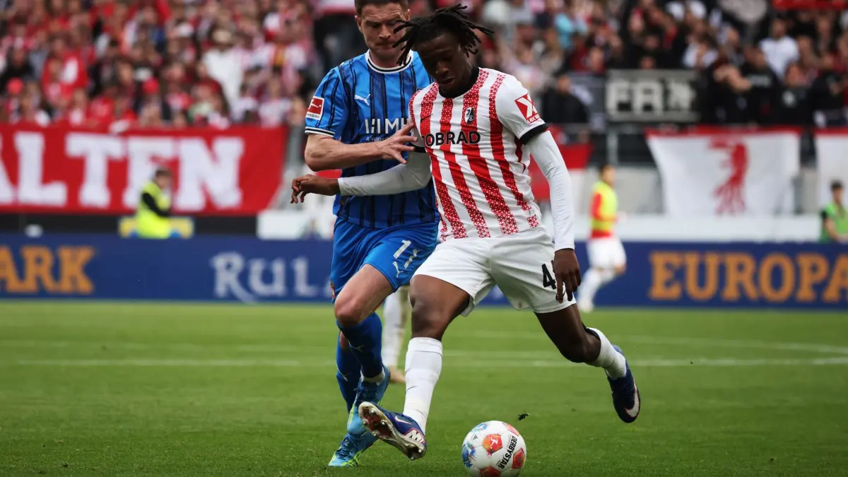 SC Freiburg - 1. FC Heidenheim: 19.04.2026, Baden-Württemberg, Freiburg im Breisgau: Fußball, Männer: Bundesliga, SC Freiburg - 1. FC Heidenheim, 30. Spieltag, Europa-Park Stadion: Budu Zivzivadze (1. FC Heidenheim 1846), Johan Manzambi (SC Freiburg) spielen um den Ball. Foto: Philipp von Ditfurth/dpa - WICHTIGER HINWEIS: Gemäß den Vorgaben der DFL Deutsche Fußball Liga bzw. des DFB Deutscher Fußball-Bund ist es untersagt, in dem Stadion und/oder vom Spiel angefertigte Fotoaufnahmen in Form von Sequenzbildern und/oder videoähnlichen Fotostrecken zu verwerten bzw. verwerten zu lassen. +++ dpa-Bildfunk +++