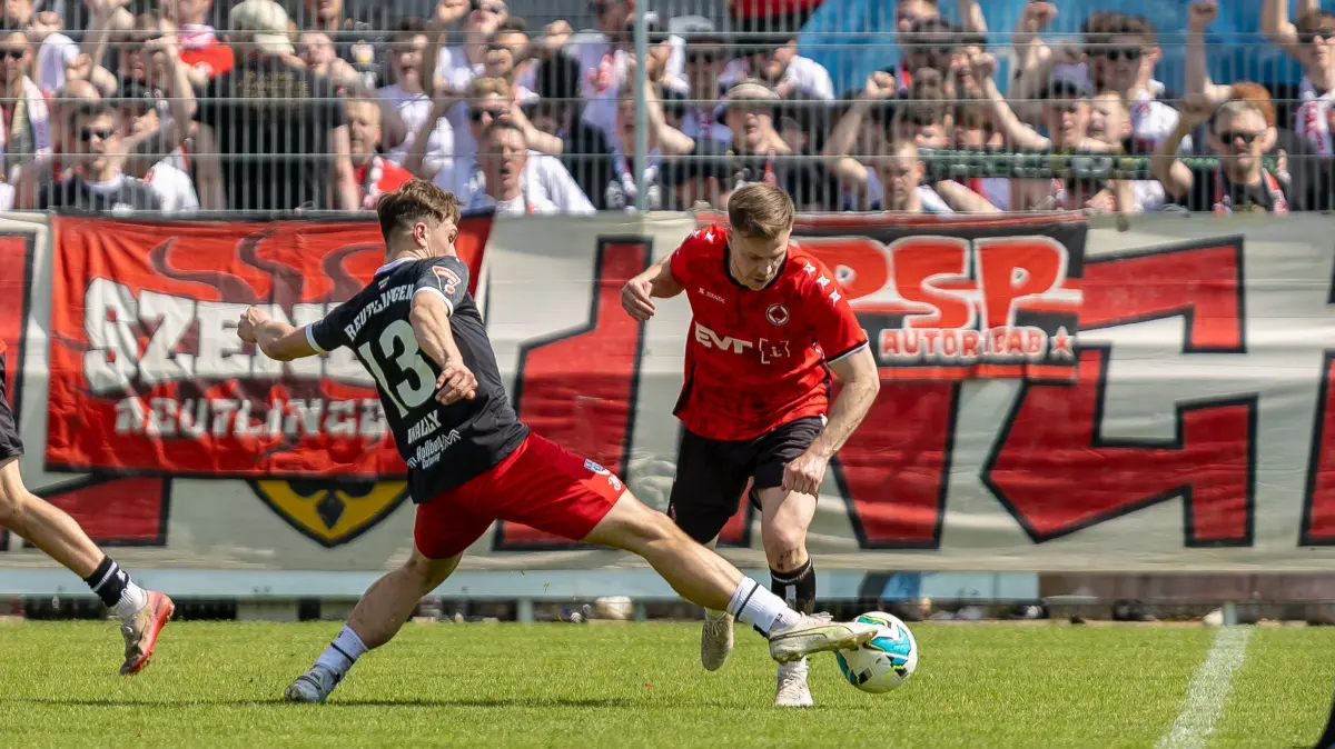 Harter Zweikampf zwischen Johannes Wally (SSV Reutlingen 05, #13) Denis Luebke (1. Goeppinger SV, #23) im Hintergrund Reutlinger Ultras Fans,
GER, 1. Goeppinger SV vs. SSV Reutlingen, Fussball, Oberliga BW, 28. Spieltag, Spielzeit 2025/2026, 18.04.2026,
Foto: Eibner-Pressefoto/Jani Pless