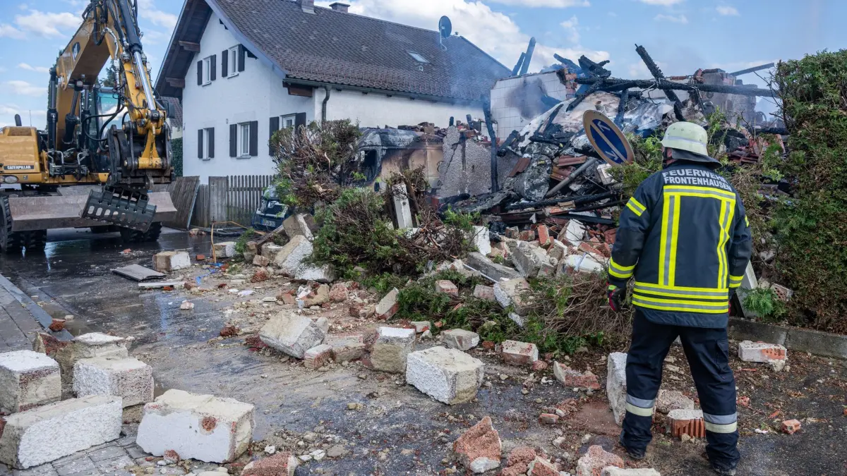 Mutmaßliche Gasexplosion in Wohnhaus: 20.04.2026, Bayern, Frontenhausen: Ein Feuerwehrmann steht vor den Trümmern eines Wohnhauses, in dem es mutmaßlich zu einer Gasexplosion gekommen sein soll. Das Gebäude in Frontenhausen (Landkreis Dingolfing-Landau) stand in Vollbrand, teilte die Polizei mit. Es gebe derzeit keine gesicherten Informationen, ob es bei dem Brand Verletzte oder Tote gibt, so die Sprecherin weiter. Foto: Armin Weigel/dpa +++ dpa-Bildfunk +++