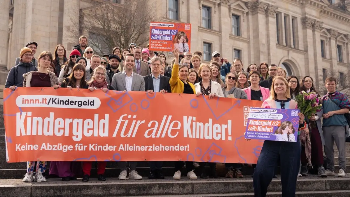 Die Initiatorin der Petition "Kindergeld für alle Kinder! Keine Abzüge für Kinder Alleinerziehender" Delia Keller steht bei der Petitionsübergabe vor Mitstreitern und Abgeordneten aus Koalition und Opposition vor dem Bundestag.