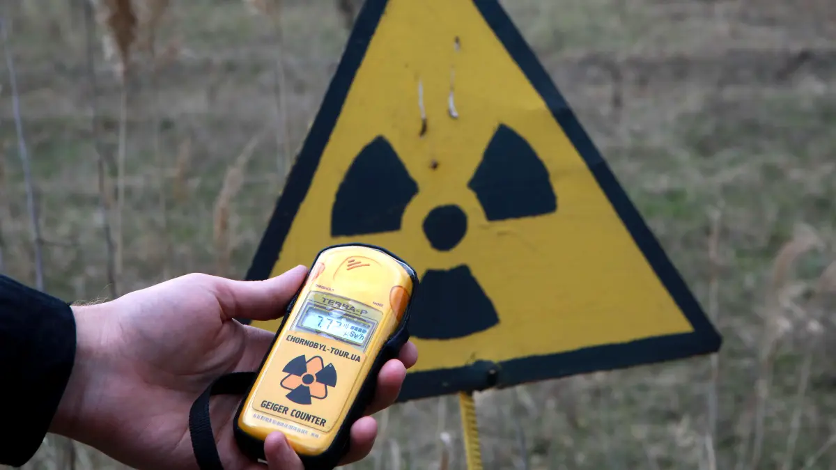 Eine Person hält einen Geigerzähler vor ein Warnschild in der heutigen Ukraine in der Nähe von Tschernobyl. Wie hoch war die Strahlung in der DDR? Jeder Soldat musste damals ein Messgerät tragen (Symbolbild)
