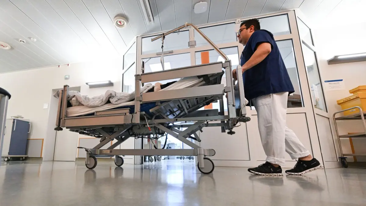Pfleger im Krankenhaus: 08.10.2025, Baden-Württemberg, Stuttgart: Ein Pfleger schiebt in einem Krankenhaus auf einer Station ein Bett mit einem Patienten. (zu dpa: «Deutsche wollen mehr Geld für Straßen – Klimaschutz verliert») Foto: Bernd Weißbrod/dpa +++ dpa-Bildfunk +++