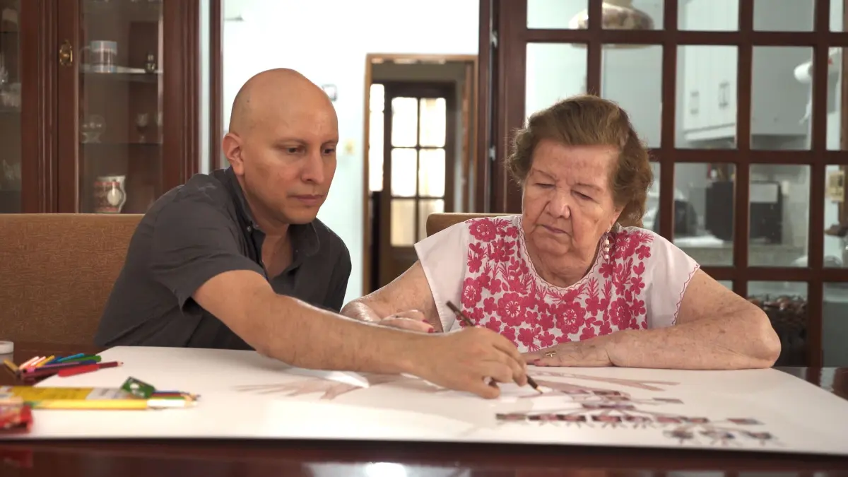 Regisseur Darío Aguirre und seine Großmutter Gloria Rodriguez sitzen vor einem Stammbaum der Familie.