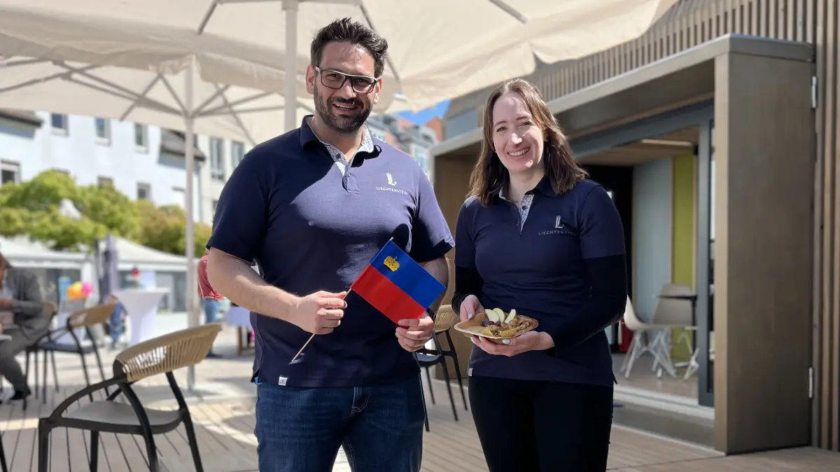 Daniel Mauche und Vanessa Kehl von präsentieren frisch zubereitendes Riebel sowie eine Fahne von Liechtenstein.