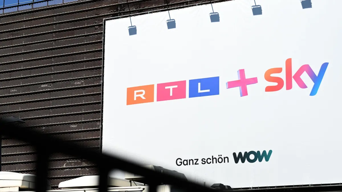 RTL Group darf Sky Deutschland übernehmen: 23.04.2026, Nordrhein-Westfalen, Köln: Ein Plakat mit der Aufschrift «RTL+ Sky - Ganz schön WOW» hängt an der Einfahrt eines Parkhauses auf dem Gelände von RTL Deutschland. Die RTL Group darf Sky Deutschland übernehmen, nachdem die EU-Kommission nach wettbewerbsrechtlicher Prüfung grünes Licht für die Transaktion gegeben hat. (zu dpa: «RTL stellt neue Geschäftsführung nach Sky-Freigabe vor») Foto: Celine Frohnapfel/dpa +++ dpa-Bildfunk +++
