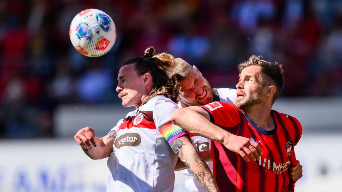 1. FC Heidenheim - FC St. Pauli: 25.04.2026, Baden-Württemberg, Heidenheim: Fußball, Männer: Bundesliga, 1. FC Heidenheim - FC St. Pauli, 31. Spieltag, Voith-Arena. Jackson Irvine (l, FC St. Pauli) und Hauke Wahl (M, FC St. Pauli) in Aktion gegen Marvin Pieringer (1. FC Heidenheim 1846). Foto: Tom Weller/dpa - WICHTIGER HINWEIS: Gemäß den Vorgaben der DFL Deutsche Fußball Liga bzw. des DFB Deutscher Fußball-Bund ist es untersagt, in dem Stadion und/oder vom Spiel angefertigte Fotoaufnahmen in Form von Sequenzbildern und/oder videoähnlichen Fotostrecken zu verwerten bzw. verwerten zu lassen. +++ dpa-Bildfunk +++