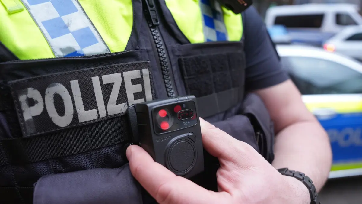ARCHIV - 15.03.2024, Hamburg: ILLUSTRATION - Ein Polizist - hier in Hamburg - greift an eine Bodycam an seiner Weste. (zu dpa: «Gewalt vorbeugen - Bodycams bei Polizei und DB-Sicherheit») Foto: Marcus Brandt/dpa +++ dpa-Bildfunk +++