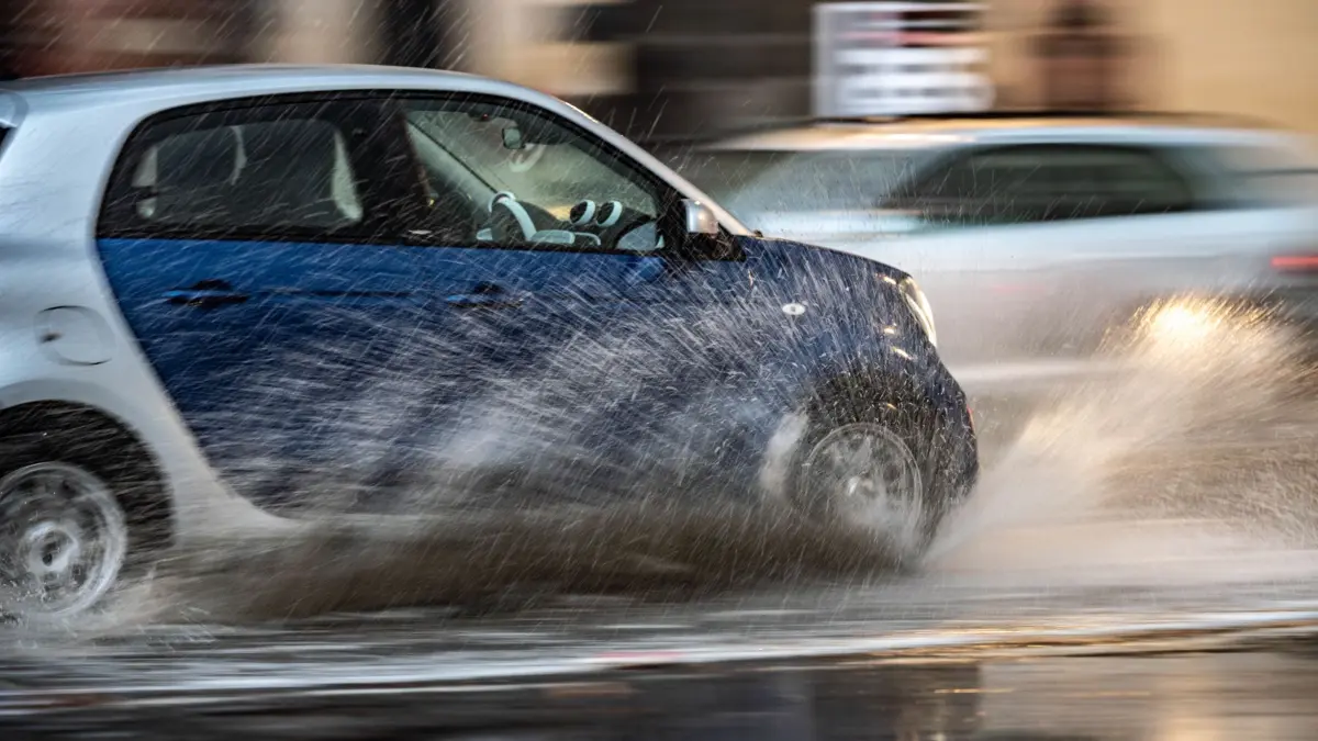 Ein Auto fährt im Regen: ARCHIV - Plötzlicher Wetterumschwung mit Starkregen? Bei Aquaplaning sollte das Auto nicht abrupt gelenkt, gebremst oder beschleunigt werden. (zu dpa: «Wechselhaftes Wetter: So kommen Autofahrer sicher an») Foto: Frank Rumpenhorst/dpa/dpa-tmn - Honorarfrei nur für Bezieher des dpa-Themendienstes +++ dpa-Themendienst +++