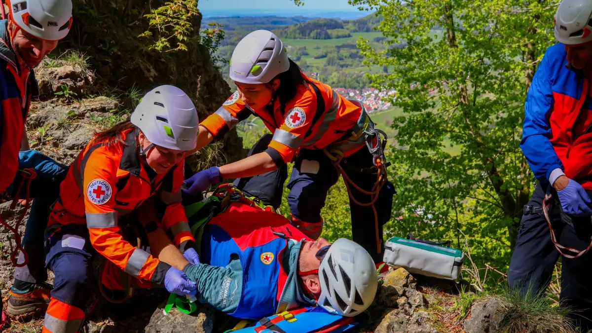 Am heutigen Vormittag fand die gemeinsame Jahresuebung der Bergwacht Goeppingen und des Deutsches Rotes Kreuz statt. Zwischen 9:30 Uhr und 12:30 Uhr wurden dabei zwei realitaetsnahe Einsatzszenarien trainiert. Ziel war es, die Zusammenarbeit beider Organisationen weiter zu staerken und Ablaeufe im schwierigen Gelaende praxisnah zu optimieren.<br />
<br />
Im ersten Szenario wurde ein abgestuerzter Bergsteiger mit schweren Verletzungen simuliert. Der Verunfallte musste zunaechst medizinisch erstversorgt werden, bevor ein sicherer Abtransport aus dem Hangbereich erfolgen konnte.<br />
<br />
Das zweite Szenario stellte die Einsatzkraefte vor eine technische Rettung aus dem Fels. Hier hatte sich ein Bergsteiger beim Klettern verletzt und einen offenen Armbruch erlitten. Nach der Rettung aus dem Fels wurde der Patient vor Ort durch das DRK medizinisch versorgt.<br />
<br />
An der Uebung nahmen insgesamt 15 Kraefte der Bergwacht Goeppingen teil, darunter auch zwei Mitglieder der Bergwacht-Jugend. Das Deutsches Rotes Kreuz war mit fuenf Kraeften vertreten – vier Auszubildenden sowie einem Praxisanleiter der Rettungswache Suessen.<br />
<br />
Die Uebung verlief sehr erfolgreich. Besonders die enge und professionelle Zusammenarbeit zwischen Bergwacht und Rettungsdienst zeigte erneut, wie wichtig eingespielte Strukturen im Ernstfall sind. Gerade fuer die Auszubildenden des DRK sind solche Lagen von hoher Bedeutung, da sie bei Einsaetzen im unwegsamen Gelaende regelmaessig eingebunden sind. Wenn Patienten durch den Rettungsdienst allein nicht geborgen werden koennen, wird die Bergwacht zur technischen Unterstuetzung alarmiert.