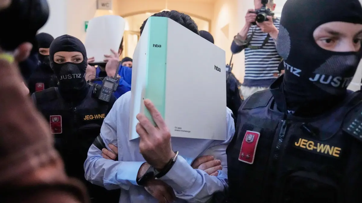 Prozess um mutmaßlichen Anschlag auf Swift-Konzert startet: 28.04.2026, Österreich, Wiener Neustadt: Zwei Angeklagte verbergen ihre Gesichter hinter Aktenordnern auf dem Weg in den Gerichtssaal des Bezirksgerichts. Einer von ihnen soll einen Anschlag auf ein Konzert von Superstar-Sängerin Taylor Swift in Wien im August 2024 geplant und sich zur Gruppe Islamischer Staat bekannt haben. Foto: Matthias Schrader/AP/dpa +++ dpa-Bildfunk +++