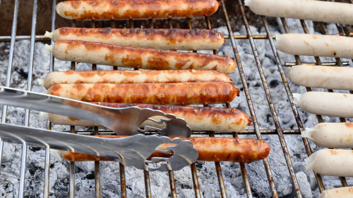 Würstchen auf dem Grill: ARCHIV - 14.02.2026, Brandenburg, Britz: Eberswalder Würstchen liegen auf einem Grill bei der «Trauerfeier» für den Eberswalder Wurst-Traditionsbetrieb. (zu dpa: «Schwere Grillunfälle sind selten») Foto: Patrick Pleul/dpa +++ dpa-Bildfunk +++