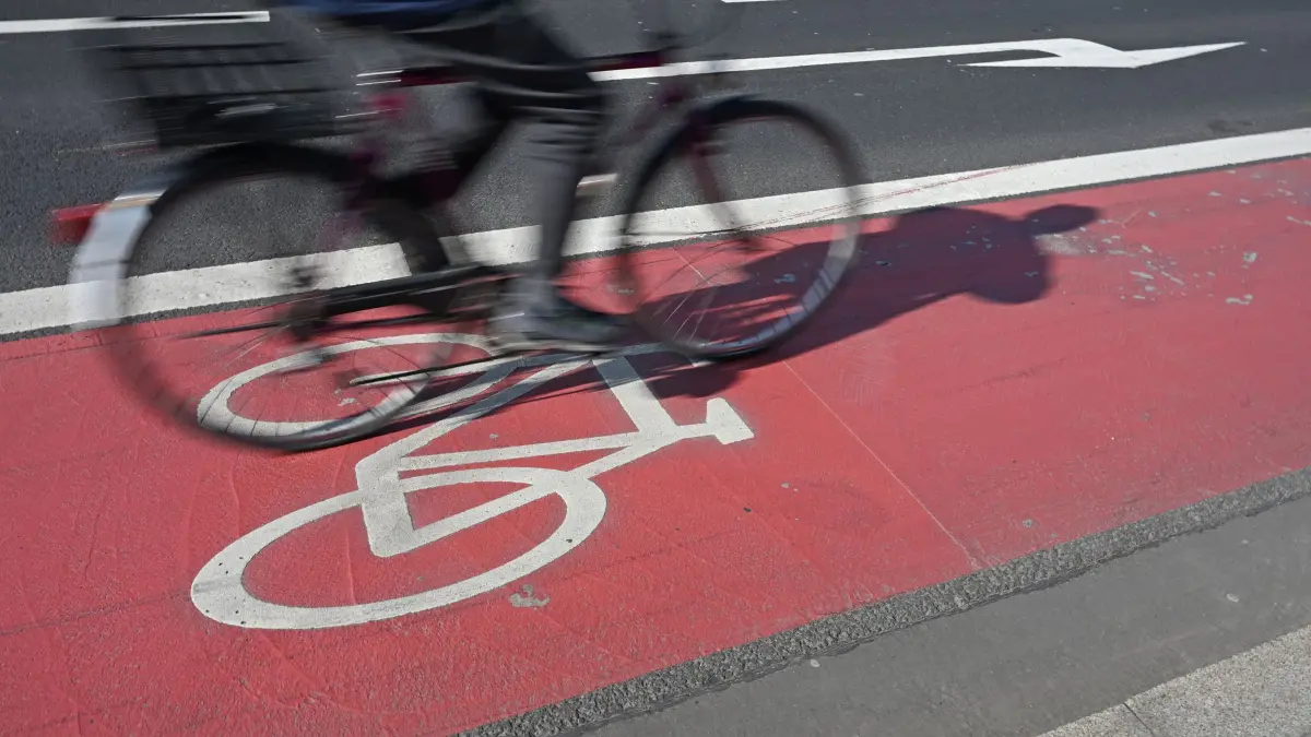 Fahrradweg: PRODUKTION - 19.03.2026, Hessen, Frankfurt/Main: Ein Fahrradfahrer fährt auf einem rot abgegrenzten Radweg mit Fahrrad-Piktogramm. (zu dpa: «Grüne wollen Radwege-Ausbau beschleunigen») Foto: Michael Brandt/dpa +++ dpa-Bildfunk +++