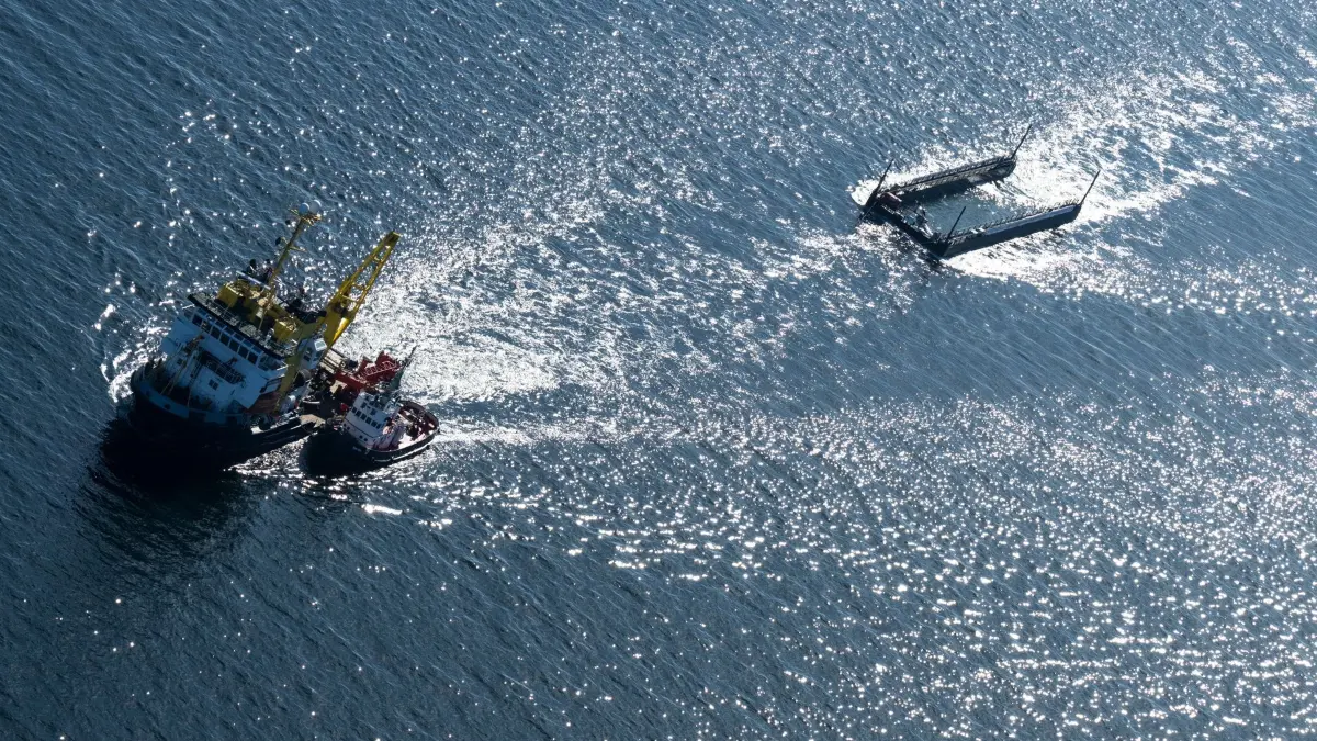 Weitere Entwicklung zum Buckelwal in der Ostsee: 29.04.2026, Schleswig-Holstein, Fehmarn: Ein Schlepperverband zieht den Wal in einem mit Wasser gefüllten Lastkahn kurz vor der dänischen Grenze (Aufnahme aus einem Flugzeug). Der aus einer flachen Bucht vor Wismar geborgene Buckelwal wird in Richtung Nordsee transportiert. Der Meeressäuger hatte zuvor vier Wochen in der Bucht der Insel Poel festgesteckt. Foto: Philip Dulian/dpa +++ dpa-Bildfunk +++