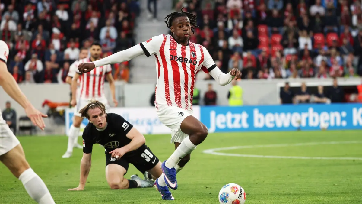 SC Freiburg - VfL Wolfsburg: 03.05.2026, Baden-Württemberg, Freiburg im Breisgau: Fußball, Männer: Bundesliga, SC Freiburg - VfL Wolfsburg, 32. Spieltag, Europa-Park Stadion: Johan Manzambi (r, SC Freiburg) erobert den Ball während Patrick Wimmer (l, VfL Wolfsburg) am Boden kniet. Foto: Philipp von Ditfurth/dpa - WICHTIGER HINWEIS: Gemäß den Vorgaben der DFL Deutsche Fußball Liga bzw. des DFB Deutscher Fußball-Bund ist es untersagt, in dem Stadion und/oder vom Spiel angefertigte Fotoaufnahmen in Form von Sequenzbildern und/oder videoähnlichen Fotostrecken zu verwerten bzw. verwerten zu lassen. +++ dpa-Bildfunk +++