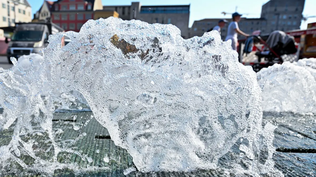 Springbrunnen in Halle: ARCHIV - 04.09.2024, Sachsen-Anhalt, Halle (Saale): Passanten gehen hinter einem Springbrunnen über den Markt in Halle/Saale. (zu dpa: «Sachsen-Anhalts Städte starten in die Brunnensaison») Foto: Hendrik Schmidt/dpa +++ dpa-Bildfunk +++