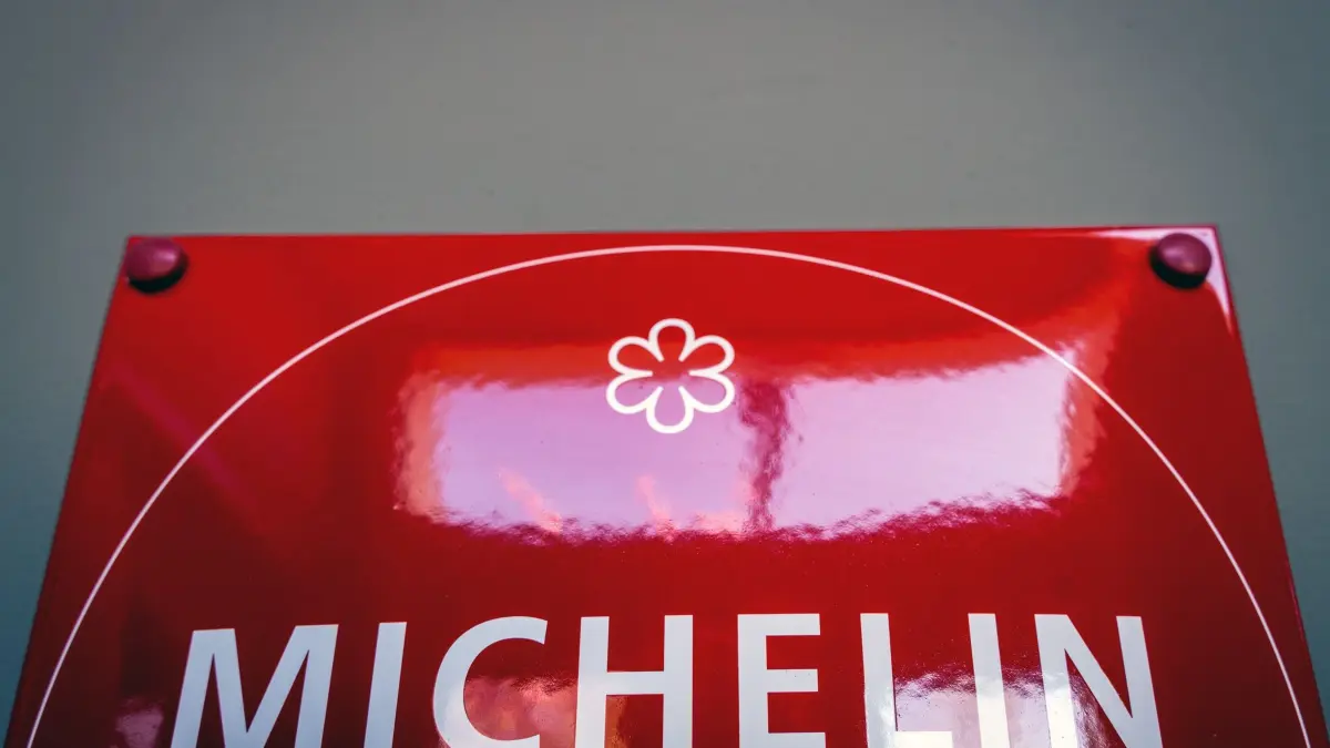 Restaurant „Alte Überfahrt“ in Werder: PRODUKTION - 23.04.2026, Brandenburg, Werder (Havel): Ein rotes Schild mit der Aufschrift „Michelin“ hängt im Eingangsbereich des an der Uferpromenade der Insel Werder gelegenen Restaurants „Alte Überfahrt“. Im Jahr 2022 bekam das Restaurant einen Michelin-Stern sowie den grünen Michelin-Stern für Gastronomie und Nachhaltigkeit. (zu dpa: «Wenn der Gast das Handy zückt - was sagen Sterne-Köche?») Foto: Soeren Stache/dpa +++ dpa-Bildfunk +++