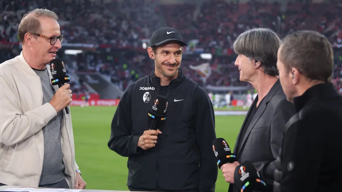 SC Freiburg - SC Braga: 07.05.2026, Baden-Württemberg, Freiburg im Breisgau: Fußball, Männer: Europa League, SC Freiburg - SC Braga, K.o.-Runde, Halbfinale, Rückspiele, Europa Park Stadion. Florian König, TV-Kommentator von RTL (l-r), Trainer Julian Schuster (SC Freiburg), der ehemalige Fußball-Bundestrainer Joachim Löw und Lothar Matthäus, TV-Experte, stehen vor dem Siel beim Interview. Foto: Philipp von Ditfurth/dpa +++ dpa-Bildfunk +++