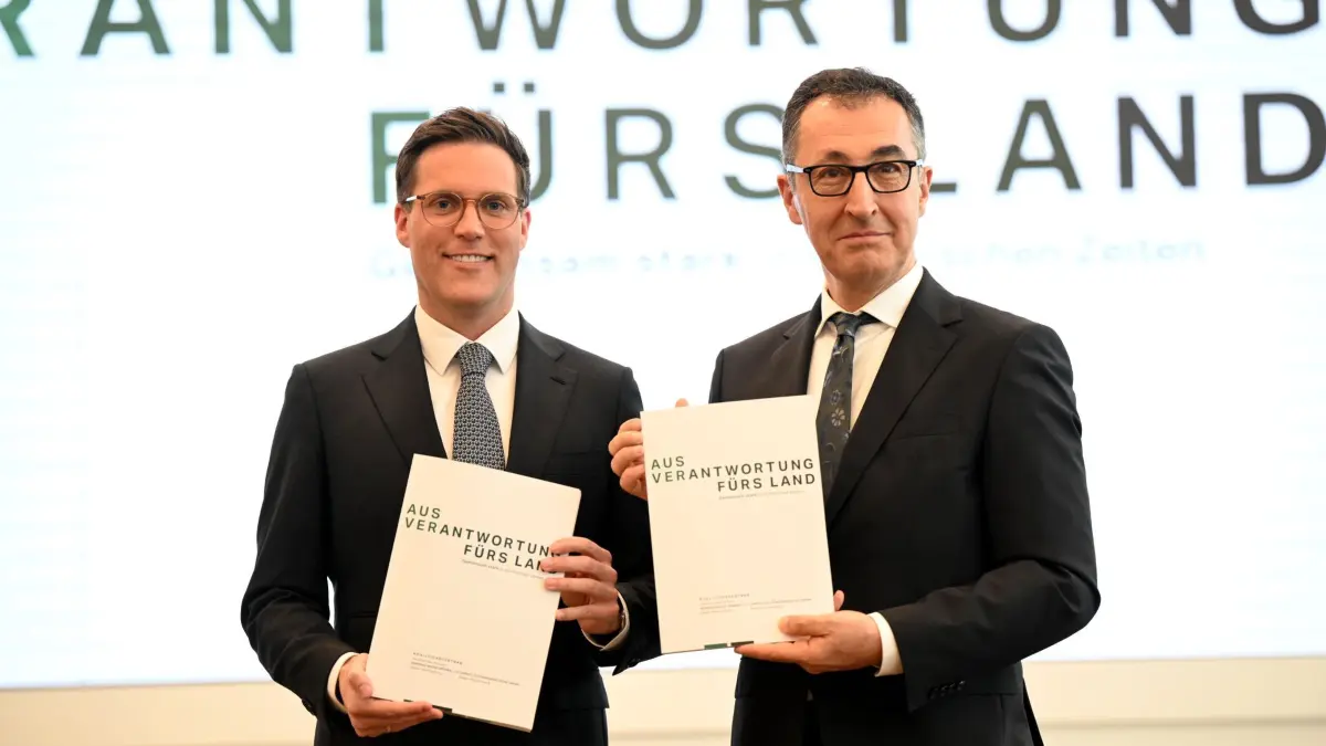 Vorstellung Koalitionsvertrag in Baden-Württemberg: 06.05.2026, Baden-Württemberg, Stuttgart: Cem Özdemir (r, Bündnis 90 / Die Grünen) und Manuel Hagel (CDU) nehmen in der Sparkassenakademie Baden-Württemberg an der Präsentation des Koalitionsvertrags von Grünen und CDU teil und zeigen den Vertrag. (zu dpa: «Grüne und CDU wollen Koalitionsvertrag beschließen») Foto: Bernd Weißbrod/dpa +++ dpa-Bildfunk +++