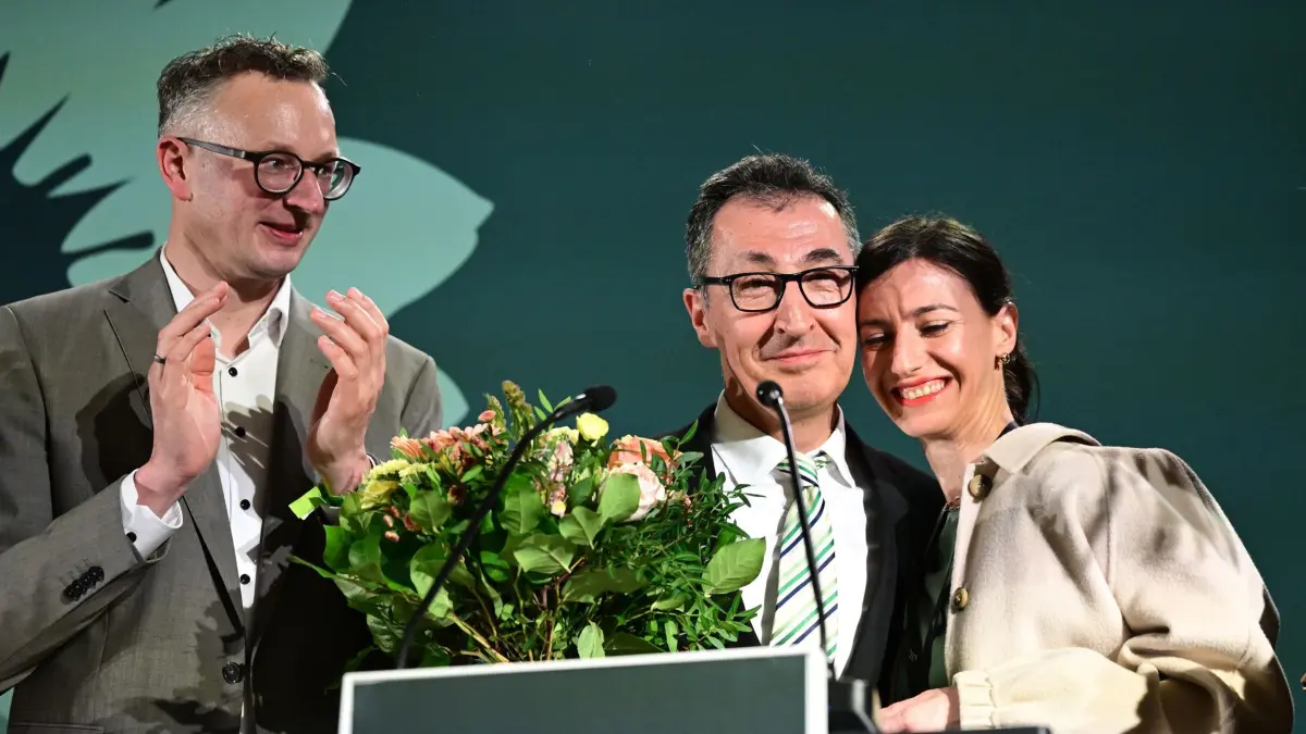 08.03.2026, Baden-Württemberg, Stuttgart: Cem Özdemir (Bündnis 90/Die Grünen, M), Spitzenkandidat Landtagswahl Baden-Württemberg, Andreas Schwarz (Bündnis 90/Die Grünen), Fraktionsvorsitzender Landtag Baden-Württemberg, und Flavia Zaka, Frau von Cem Özdemir, stehen bei der Wahlparty der Grünen auf der Bühne. Am 8. März fand in Baden-Württemberg die Landtagswahl statt. Foto: Bernd Weißbrod/dpa +++ dpa-Bildfunk +++