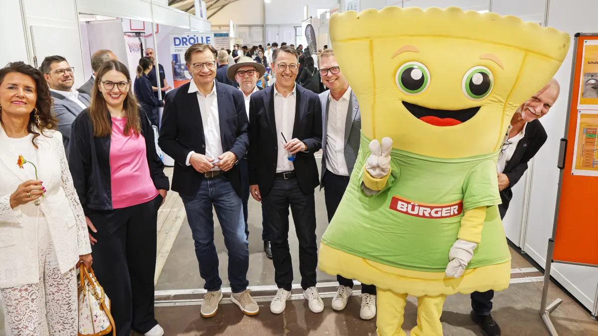 Der gut gelaunte Organisator Eberhard Spies (ganz rechts) spickelt hinter dem Maultaschen-Maskottchen der Crailsheimer Firma Bürger hervor. Er und seine Mitstreiter freuen sich über eine gelungene Jobbörse 2026.