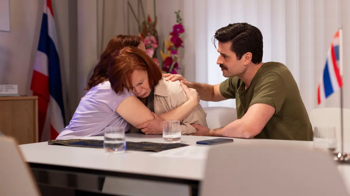 Irene (Petra Blossey, M.) trifft es hart, von Roberts Tod zu erfahren. Links Anna (Marie Zielcke), rechts Paco (Milos Vukovic)