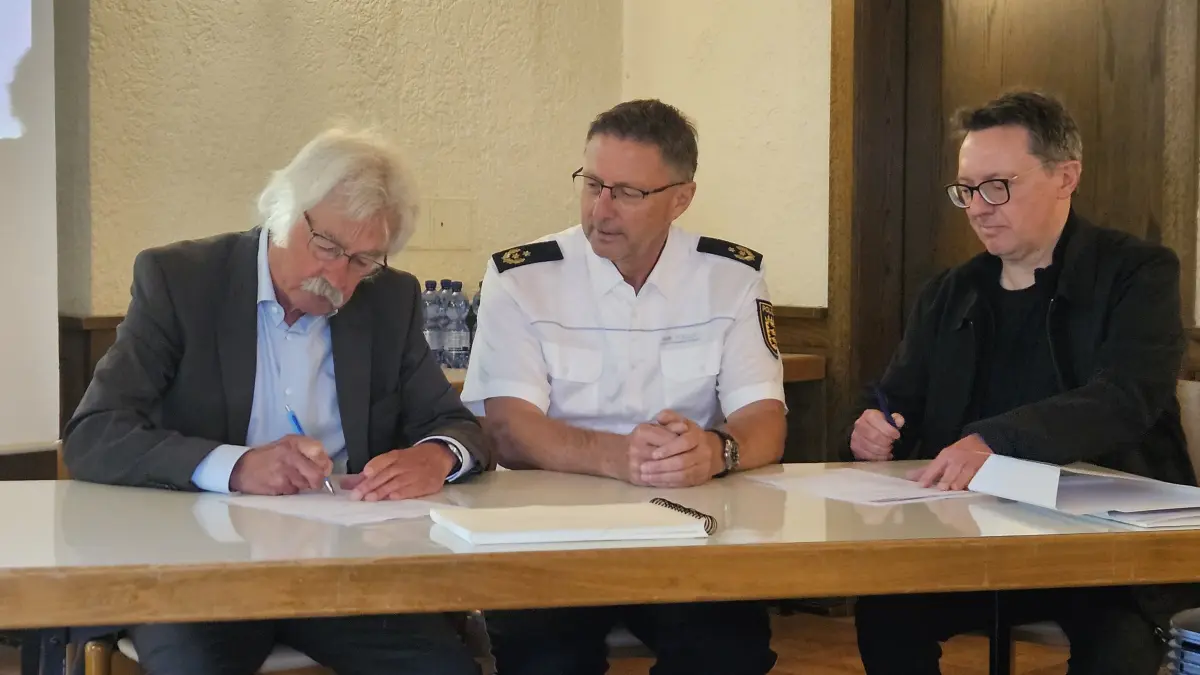 Rüdiger Böhm vom Förderverein Grafeneck, Polizeipräsident Udo Vogel vom Polizeipräsidium Reutlingen und Thomas Stöckle, Gedenkstättenleiter, unterschreiben die Kooperationsvereinbarung.