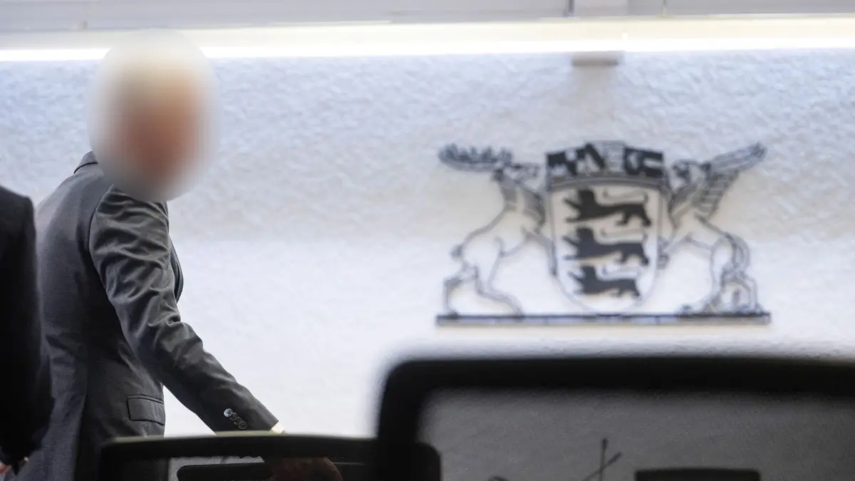 12.05.2026, Baden-Württemberg, Stuttgart: Der Angeklagte in einem Prozess wegen Bestechlichkeit steht in einem Saal des Landgerichts Stuttgart. Der vom Dienst suspendierte Inspekteur der Polizei muss erneut vor Gericht. Knapp drei Jahre nach dem Freispruch wegen des Vorwurfs der sexuellen Belästigung ist er wegen Bestechlichkeit vor dem Landgericht angeklagt. Foto: Marijan Murat/dpa - ACHTUNG: Person wurde aus rechtlichen Gründen gepixelt +++ dpa-Bildfunk +++
