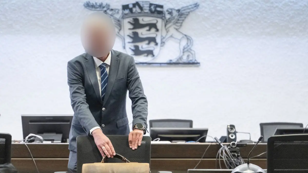 Inspekteur der Polizei steht erneut vor Gericht: 12.05.2026, Baden-Württemberg, Stuttgart: Der Angeklagte in einem Prozess wegen Bestechlichkeit steht in einem Saal des Landgerichts Stuttgart. Der vom Dienst suspendierte Inspekteur der Polizei muss erneut vor Gericht. Knapp drei Jahre nach dem Freispruch wegen des Vorwurfs der sexuellen Belästigung ist er wegen Bestechlichkeit vor dem Landgericht angeklagt. Foto: Marijan Murat/dpa - ACHTUNG: Person wurde aus rechtlichen Gründen gepixelt +++ dpa-Bildfunk +++