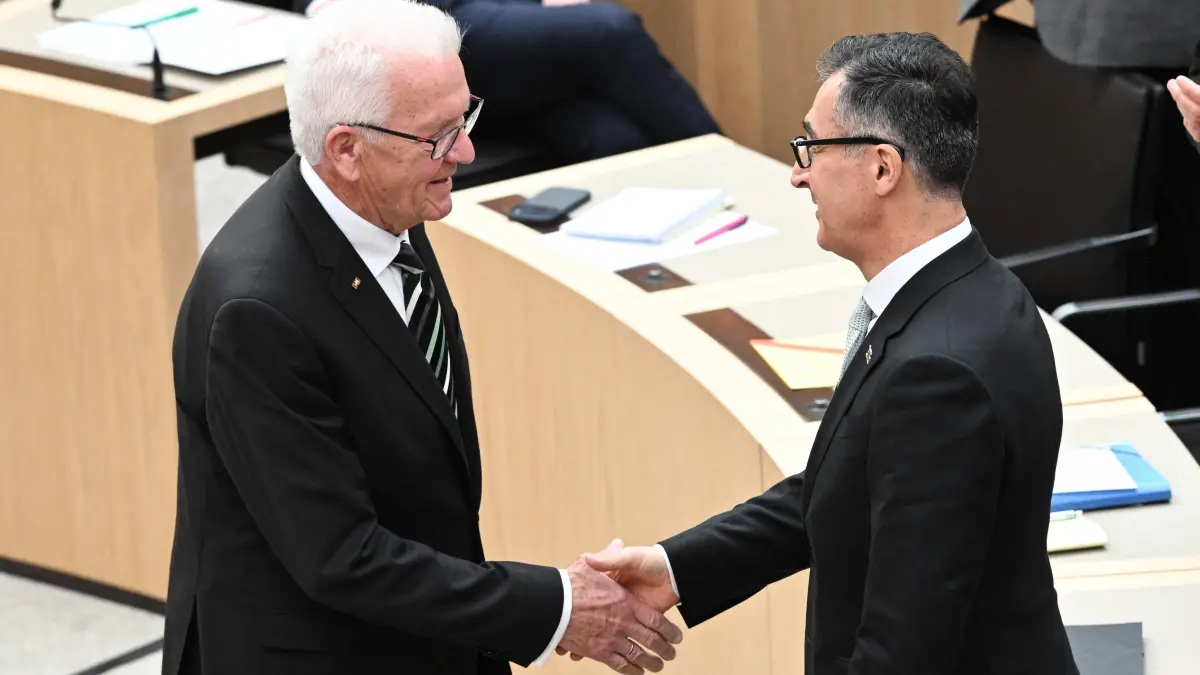 Baden-Wuerttemberg's outgoing State Premier Winfried Kretschmann (L) congratulates his successor Cem Oezdemir of the Greens after he was elected as new State Premier of Baden-Wuerttemberg in the state parliament in Stuttgart, southern Germany, on May 13, 2026. The inaugural session of the new state parliament of Baden-Wuerttemberg took place the day before, on May 12, 2026, following state elections on March 8, 2026. (Photo by THOMAS KIENZLE / AFP)