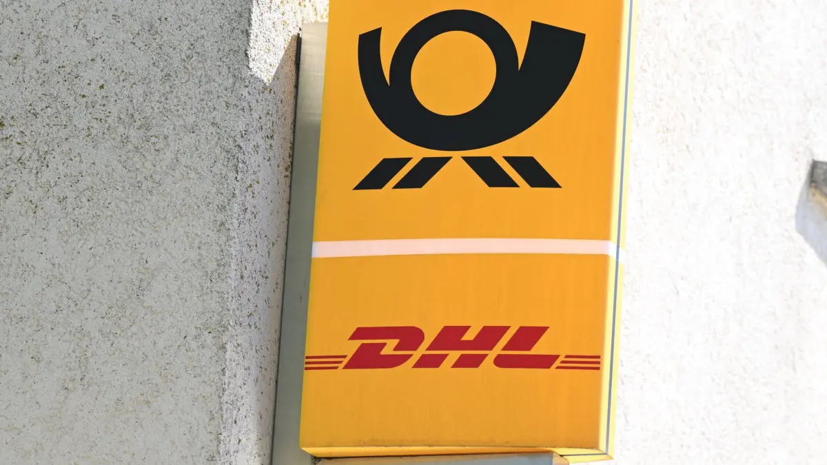 Postfiliale: ARCHIV - 17.04.2026, Baden-Württemberg, Stuttgart: Ein Schild mit den Logos der Post und DHL hängt vor einer Postfiliale. (zu dpa: «Aufregung um Post-Dienstleistungen in Schwerins Stadtzentrum») Foto: Bernd Weißbrod/dpa +++ dpa-Bildfunk +++