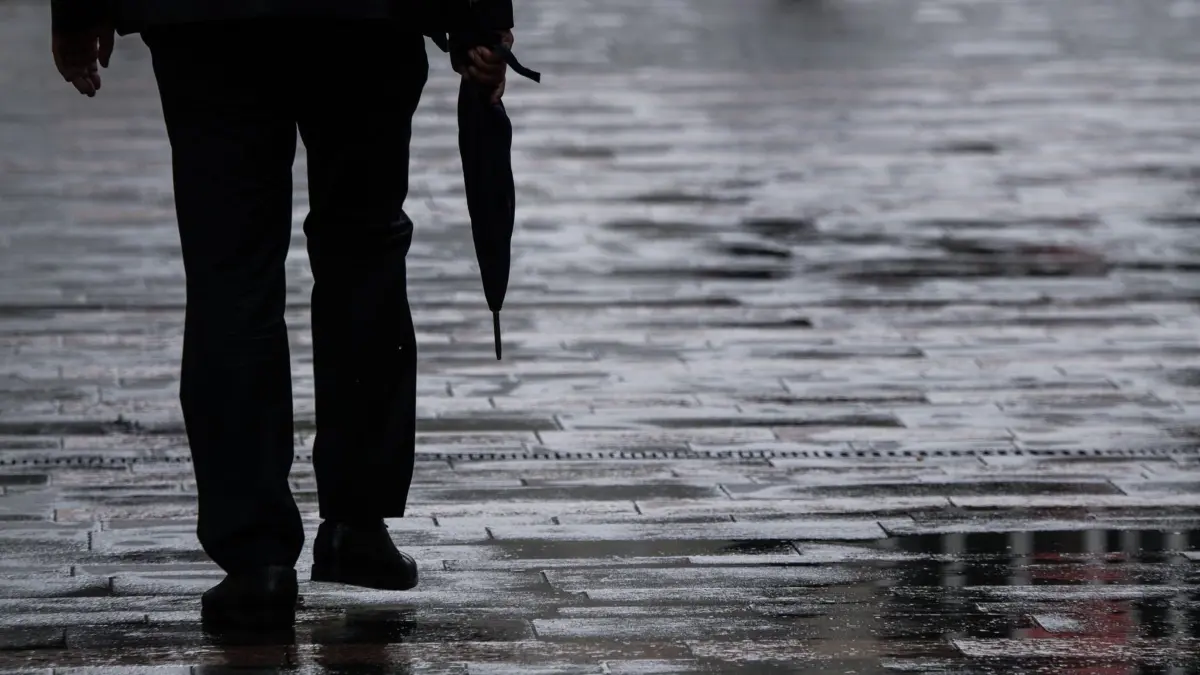 Ein Passant geht mit Regenschirm in der Hand durch Mainz: ARCHIV - 13.08.2018, Rheinland-Pfalz, Mainz: Ein Passant geht mit einem Regenschirm in der Hand durch die Mainzer Fußgängerzone. (zu dpa: «Graues und trübes Wetter setzt sich fort») Foto: Andreas Arnold/dpa +++ dpa-Bildfunk +++