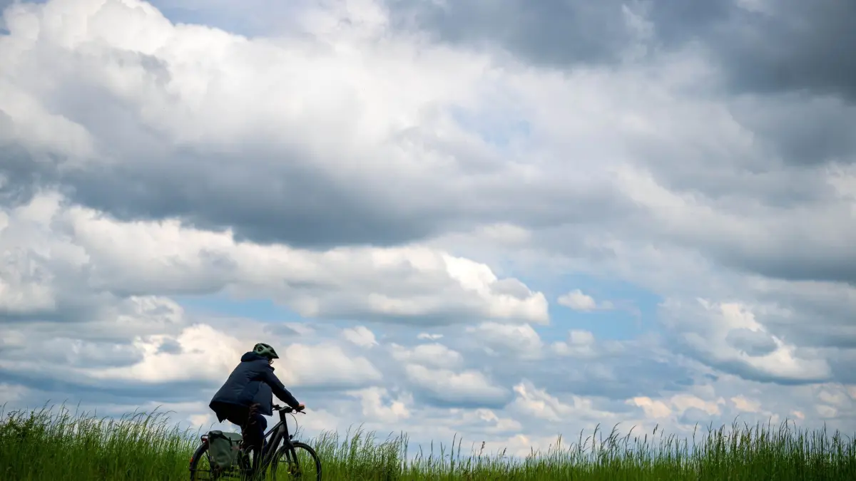 Wetter in Bremen: 18.05.2026, Bremen: Ein Radfahrer fährt bei bewölktem Himmel über einen Feldweg. Foto: Sina Schuldt/dpa +++ dpa-Bildfunk +++