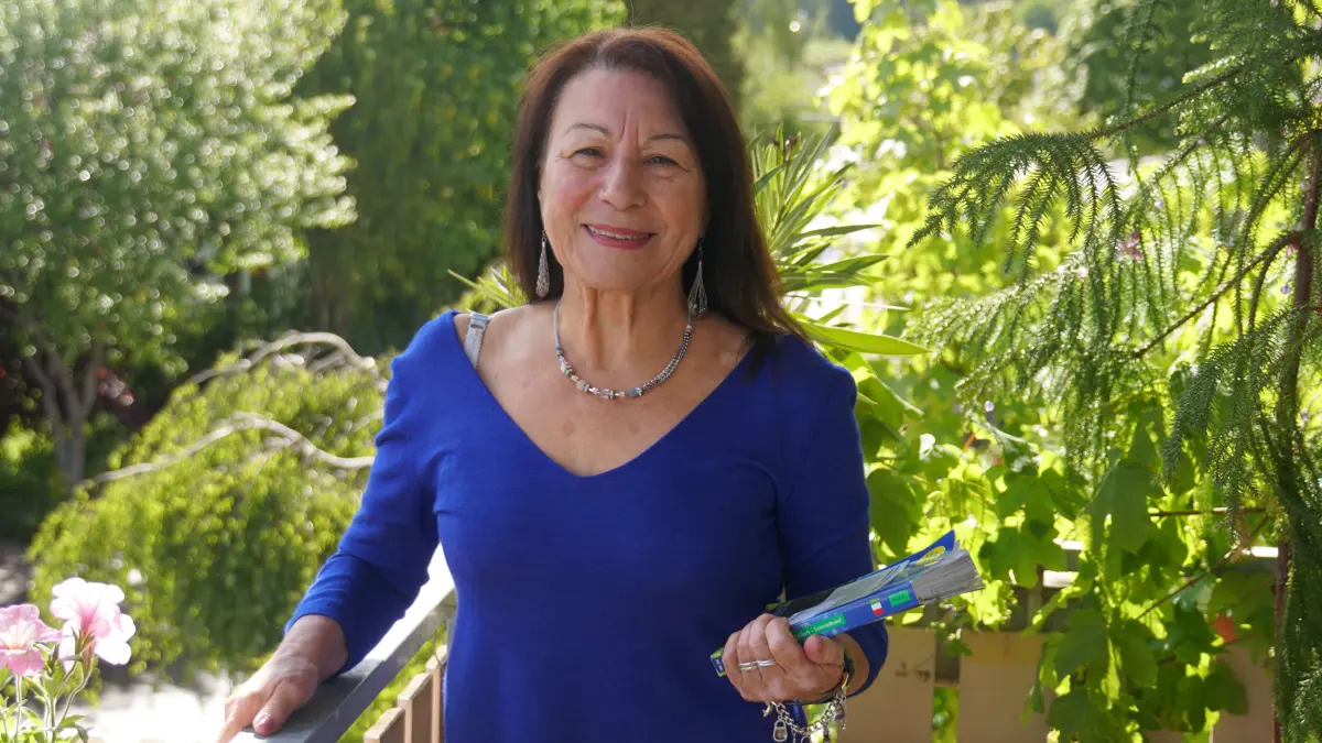 Grazia Stuber auf ihrem Balkon – das Sprachbuch in der Hand und wie so oft ein Lachen auf den Lippen.