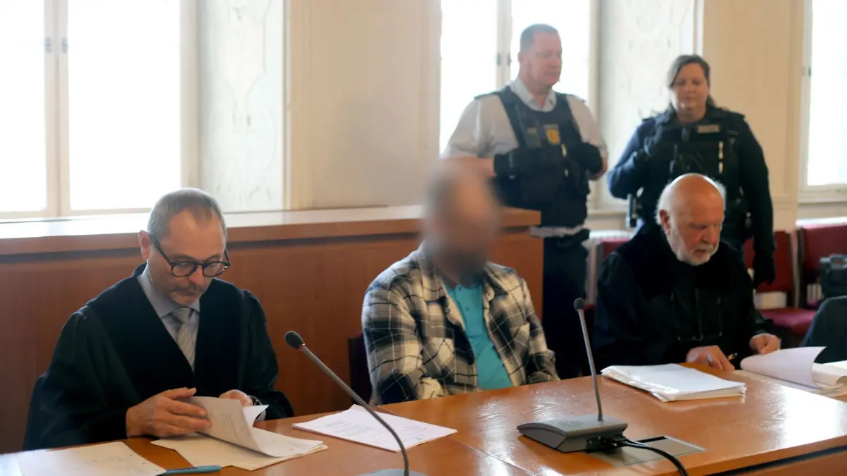 Prozess um Nachbarschaftsstreit in Ellwangen: 19.05.2026, Baden-Württemberg, Ellwangen: Der Angeklagte (M) und die Rechtsanwälte Andreas Kugel (l) und Raol Sander sitzen im Landgericht zu Beginn des Prozesses wegen versuchten Mordes. Der 47-jährige Angeklagte soll versucht haben, einen Nachbarn mit einem Hammer zu erschlagen. Foto: Uwe Kempf/dpa - ACHTUNG: Angeklagter wurde auf Ansage des Gerichts aus rechtlichen Gründen gepixelt +++ dpa-Bildfunk +++
