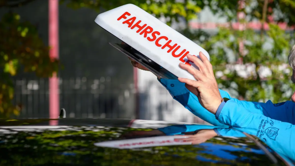 Fahrschule: ARCHIV - 25.08.2025, Sachsen-Anhalt, Magdeburg: "Fahrschule" ist auf einem Schild zu lesen das ein Fahrlehrer auf das Dach seines Autos stellt. (zu dpa: «Nächster Schritt für Führerschein-Reform: Das ist geplant») Foto: Klaus-Dietmar Gabbert/dpa +++ dpa-Bildfunk +++