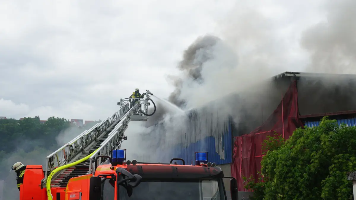 Ebersbach: Brand eines Recycling Betriebes: Heute gegen 13 Uhr wurde die Freiwillige Feuerwehr Ebersbach an der Fils zu einem Brand bei einem Recyclingbetrieb in Ebersbach an der Fils alarmiert. Bereits beim Eintreffen der ersten Einsatzkraefte waren eine starke Rauchentwicklung sowie offene Flammen sichtbar. Aufgrund der Lage wurden umgehend weitere Kraefte nachalarmiert, darunter die Freiwillige Feuerwehr Uhingen sowie die Feuerwehr Goeppingen.<br />
<br />
Im Einsatz befanden sich unter anderem eine Drehleiter sowie mehrere Atemschutztrupps. Unterstuetzung erhielt die Feuerwehr zudem direkt vom Recyclingbetrieb: Mitarbeiter rueckten mit Radladern an und halfen dabei, Metallabdeckungen zu entfernen, um den Loeschangriff zu erleichtern.<br />
<br />
Ueber die Warn-App NINA wurde eine Warnmeldung wegen Geruchsbelaestigung und starker Rauchentwicklung herausgegeben. Wie lange die Loescharbeiten und der Einsatz noch andauern werden, ist derzeit unklar.<br />
<br />
Nach ersten Informationen koennte ein entsorgter Akku den Brand ausgeloest haben. Solche Vorfaelle sollen in Recyclingbetrieben bereits mehrfach vorgekommen sein, da sich beschaedigte oder falsch entsorgte Akkus entzuenden koennen. Die genaue Ursache des Feuers wird nun von Brandermittlern der Polizei untersucht.