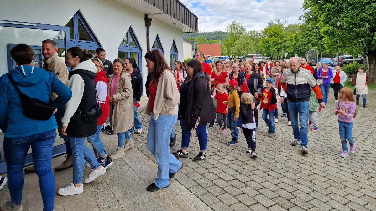 Rund 70 Eltern und Kinder ziehen zum Großteil rot gekleidet am Mittwoch in den Kernersaal der Limpurghalle ein, um ein Zeichen gegen die Erhöhung der Gebühren für die Grundschulbetreuung zu setzen.