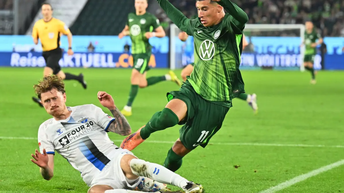 VfL Wolfsburg - SC Paderborn 07: 21.05.2026, Niedersachsen, Wolfsburg: Fußball, Männer: Bundesliga - Relegation, VfL Wolfsburg - SC Paderborn 07, Relegation, Hinspiele, Volkswagen Arena. Adam Daghim (r, VfL Wolfsburg) kämpft mit Calvin Brackelmann (l, SC Paderborn 07) um den Ball. Foto: Swen Pförtner/dpa - WICHTIGER HINWEIS: Gemäß den Vorgaben der DFL Deutsche Fußball Liga bzw. des DFB Deutscher Fußball-Bund ist es untersagt, in dem Stadion und/oder vom Spiel angefertigte Fotoaufnahmen in Form von Sequenzbildern und/oder videoähnlichen Fotostrecken zu verwerten bzw. verwerten zu lassen. +++ dpa-Bildfunk +++