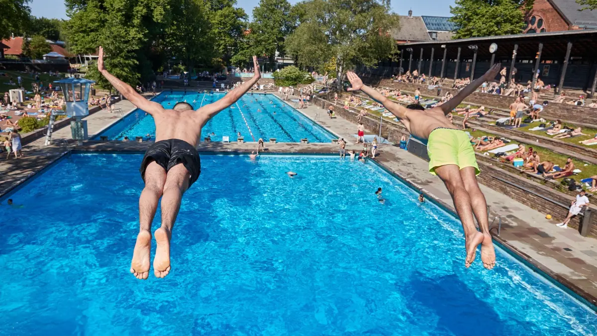 Sommerfreibad Kaifubad: ARCHIV - 07.06.2023, Hamburg: Zwei Männer springen vom Fünfmeter Turm in das Becken im Sommerfreibad Kaifu-Bad. (zu dpa: «Hamburgs Freibäder starten in die Sommersaison») Foto: Georg Wendt/dpa +++ dpa-Bildfunk +++