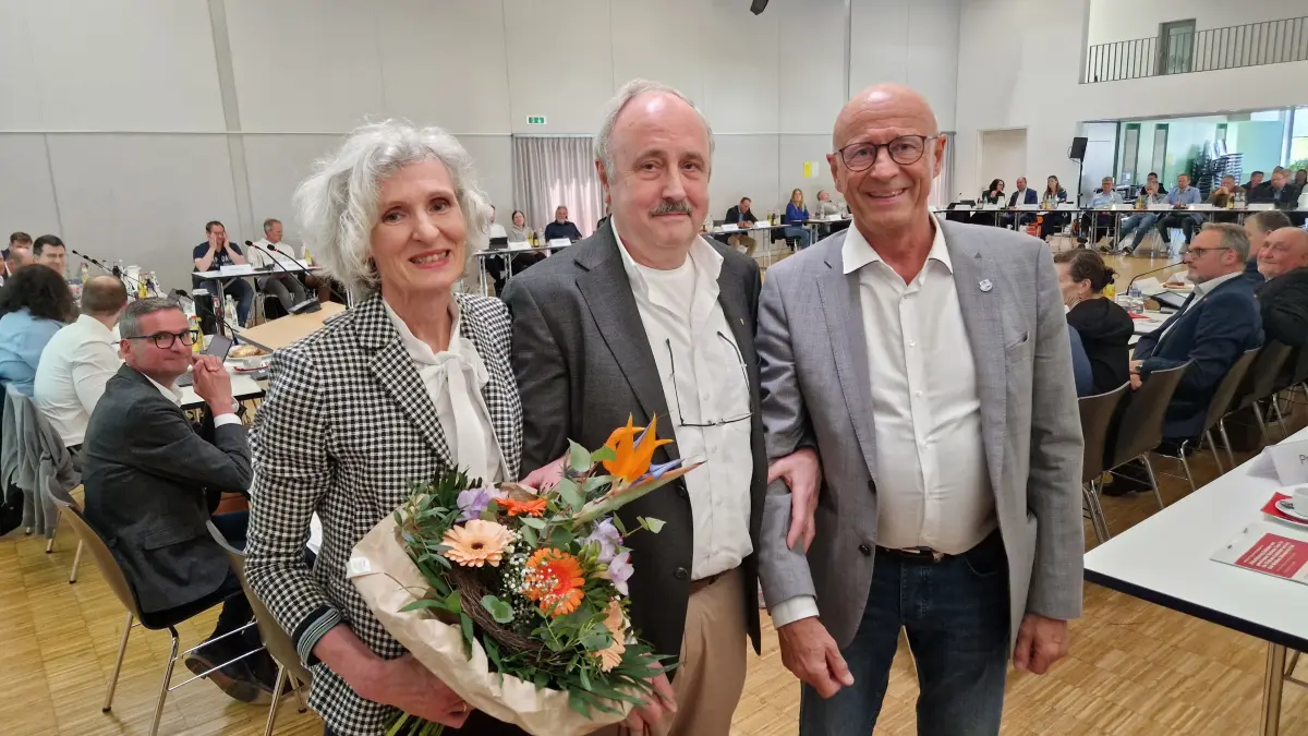 Landrat Gerhard Bauer (rechts) dankt Privatdozent Dr. Heinrich Lenders im Kreistag in Kirchberg/Jagst für „viele Jahre Spitzenmedizin in unserem Landkreis“ und überreicht Blumen an die Frau von Lenders.