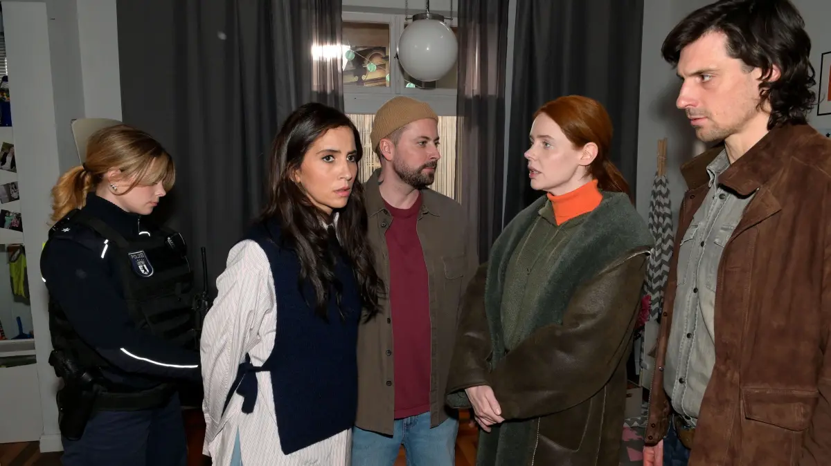 John (Felix von Jascheroff, M.) ist fassungslos, dass Laura (Chryssanthi Kavazi, 2.v.l.) verhaftet wird. Toni (Olivia Marei) und Schmitti (Timo Hastenpflug) glauben, dass sie endlich Zoes wahre Mörderin festgenommen haben.