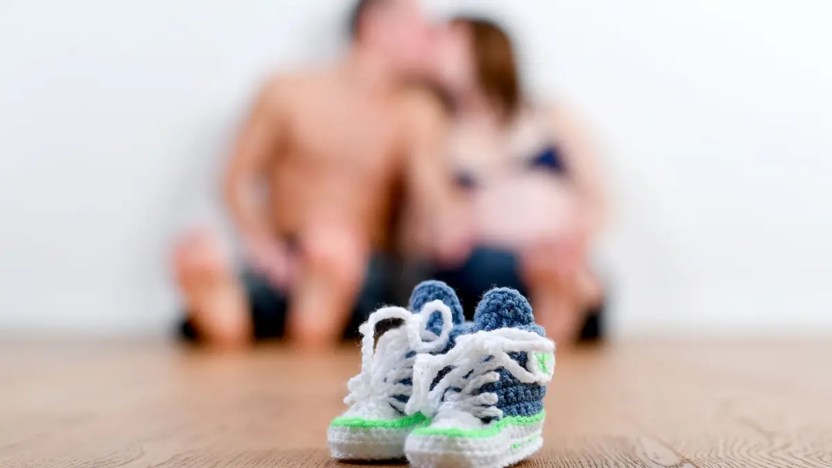 Paar küsst sich hinter Babyschuhen