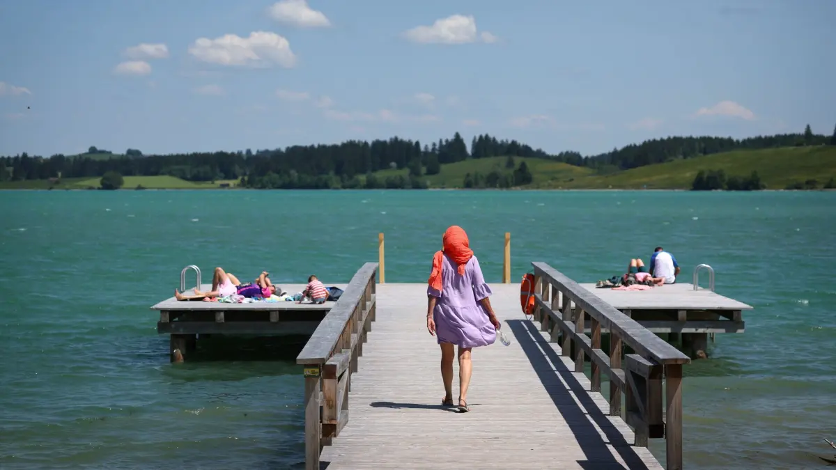 Sommerliches Wetter - Bayern: 24.05.2026, Bayern, Schwangau: Ausflügler genießen den Sonnenschein auf einem Steg am Forggensee. Foto: Karl-Josef Hildenbrand/dpa +++ dpa-Bildfunk +++