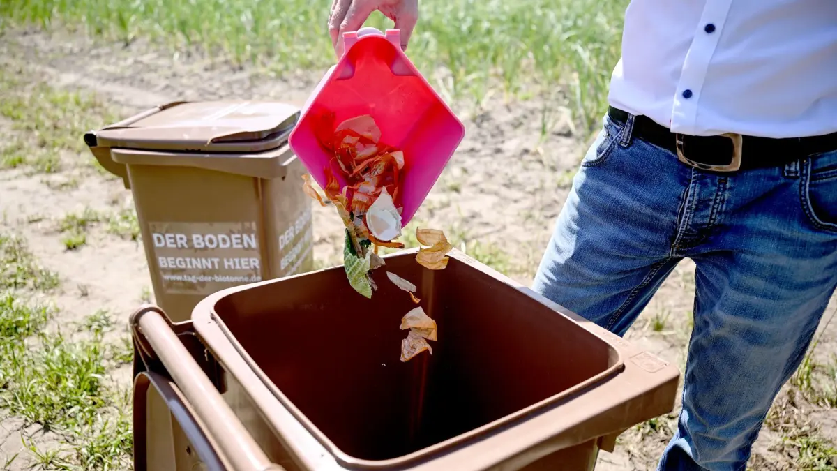 Tag der Biotonne: 26.05.2026, Berlin: Ein Teilnehmer schüttet biologischen Abfall beim Pressetermin des Bundesweiten Tag der Biotonne in die Tonne. Ziel des Tages ist es, die Bevölkerung für die Bedeutung des Biomülls zu sensibilisieren und den Beitrag für Bodenfruchtbarkeit, Ressourcenschutz, Klimaschutz sowie Unabhängigkeit von Rohstoffimporten hervorzuheben. (zu dpa: «Das sollte man in Berlin zur Biotonne wissen») Foto: Britta Pedersen/dpa +++ dpa-Bildfunk +++